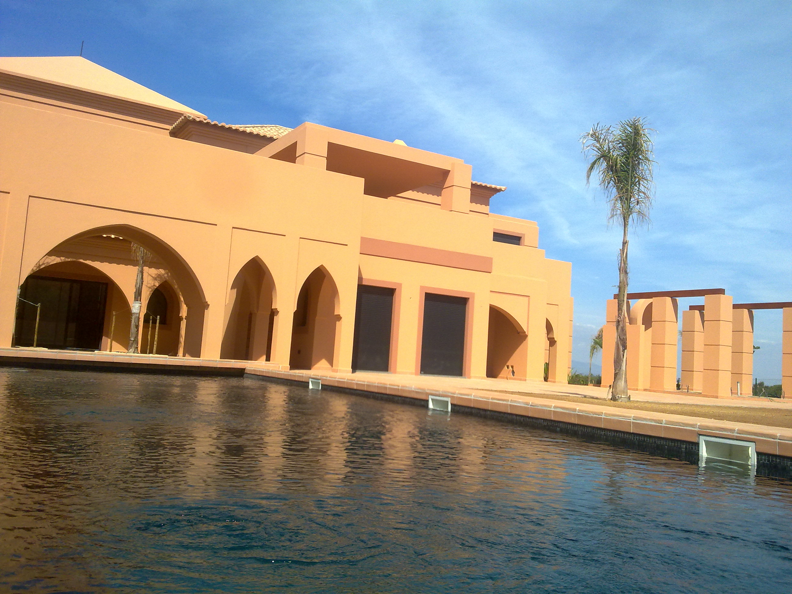 Arcos pontiagudos e terraço da Villa Kasbah refletidos na piscina