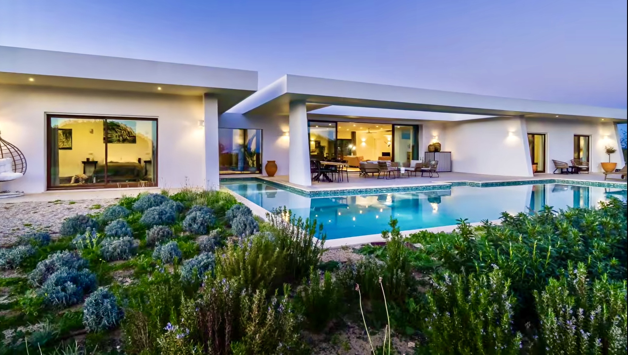 Piscina e terraço da Villa Porches vistos por entre arbustos floridos