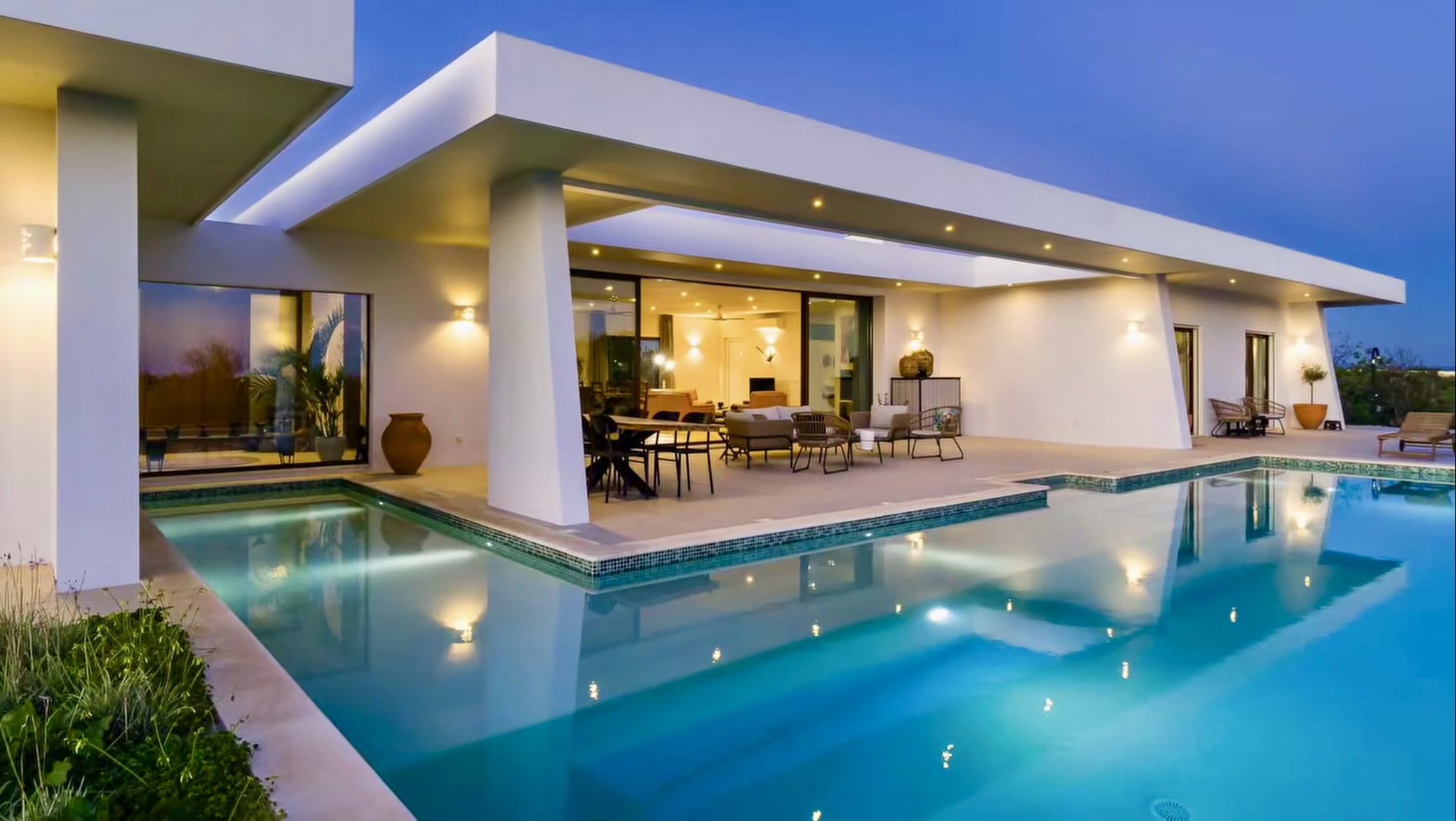 Terraço coberto e degraus da piscina na Villa Porches ao anoitecer