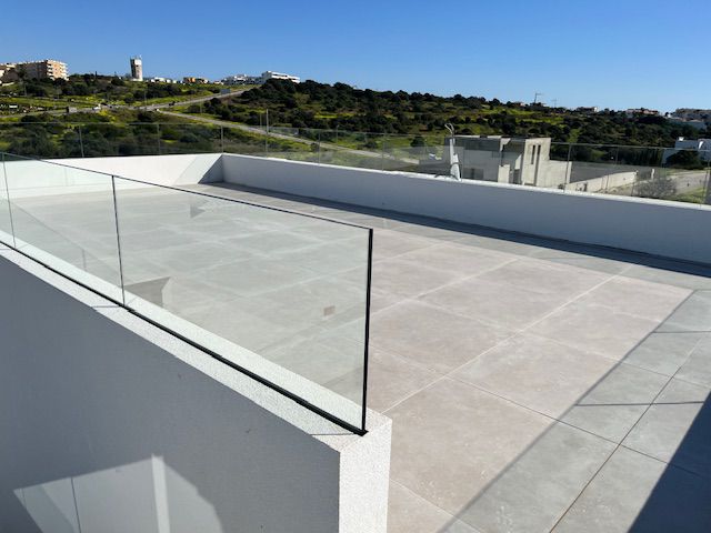Terraço na cobertura com pavimento cerâmico e guardas de vidro em Porto de Mós
