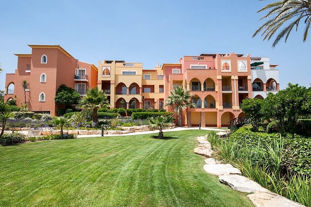 Edifícios coloridos do resort Jardim da Meia Praia junto a relvados ajardinados