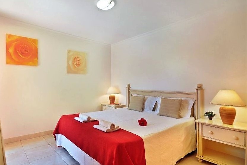 Quarto renovado com colcha vermelha no Jardim da Meia Praia